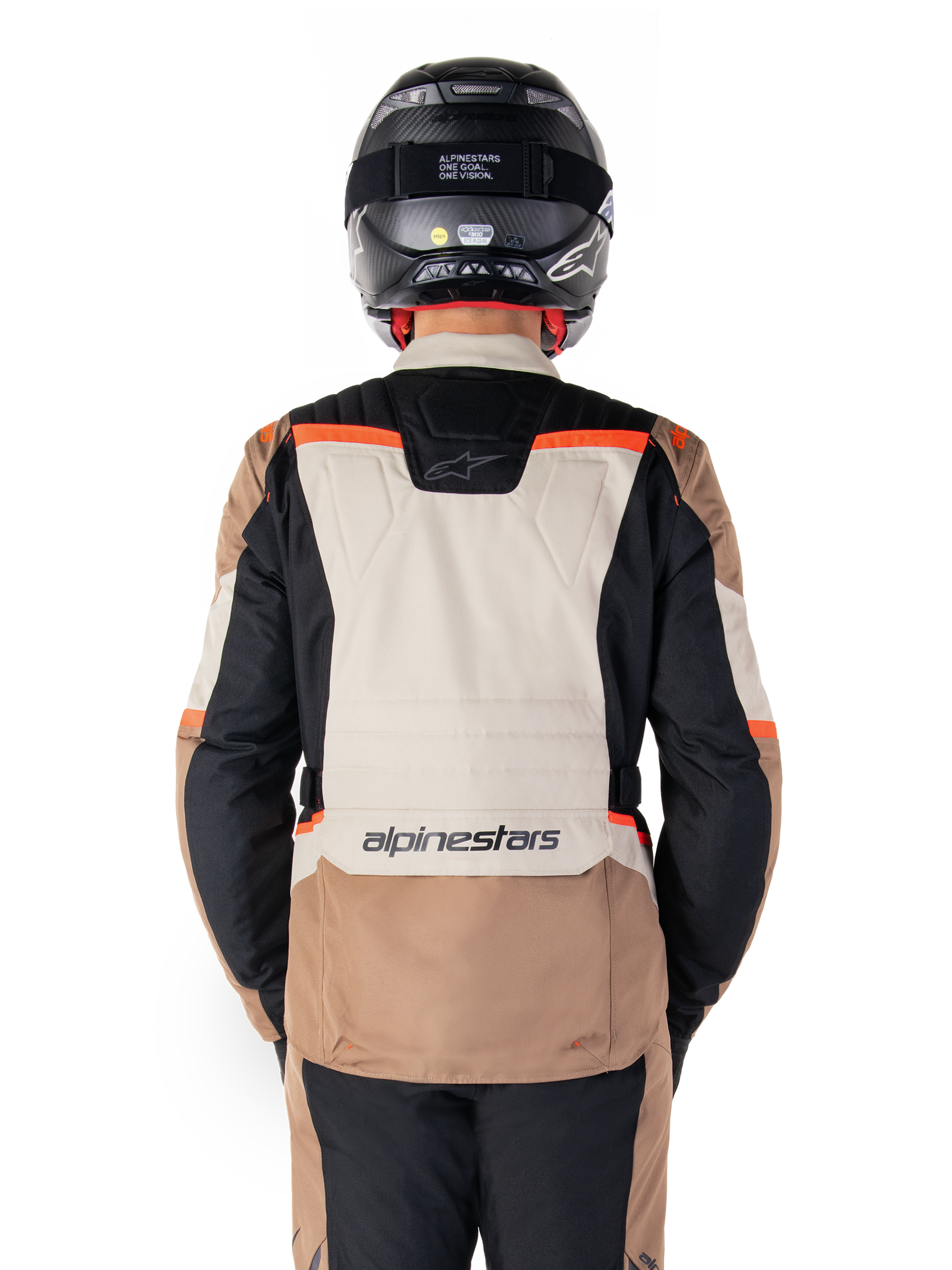 Chaqueta impermeable Alpinestars ST-1, Dark Khaki Sand Black Red Fluo, vista trasera, chaqueta de motociclismo adventure touring con un gran panel trasero de color arena, mangas negras y detalles en rojo fluorescente, mostrada en un piloto con casco negro.