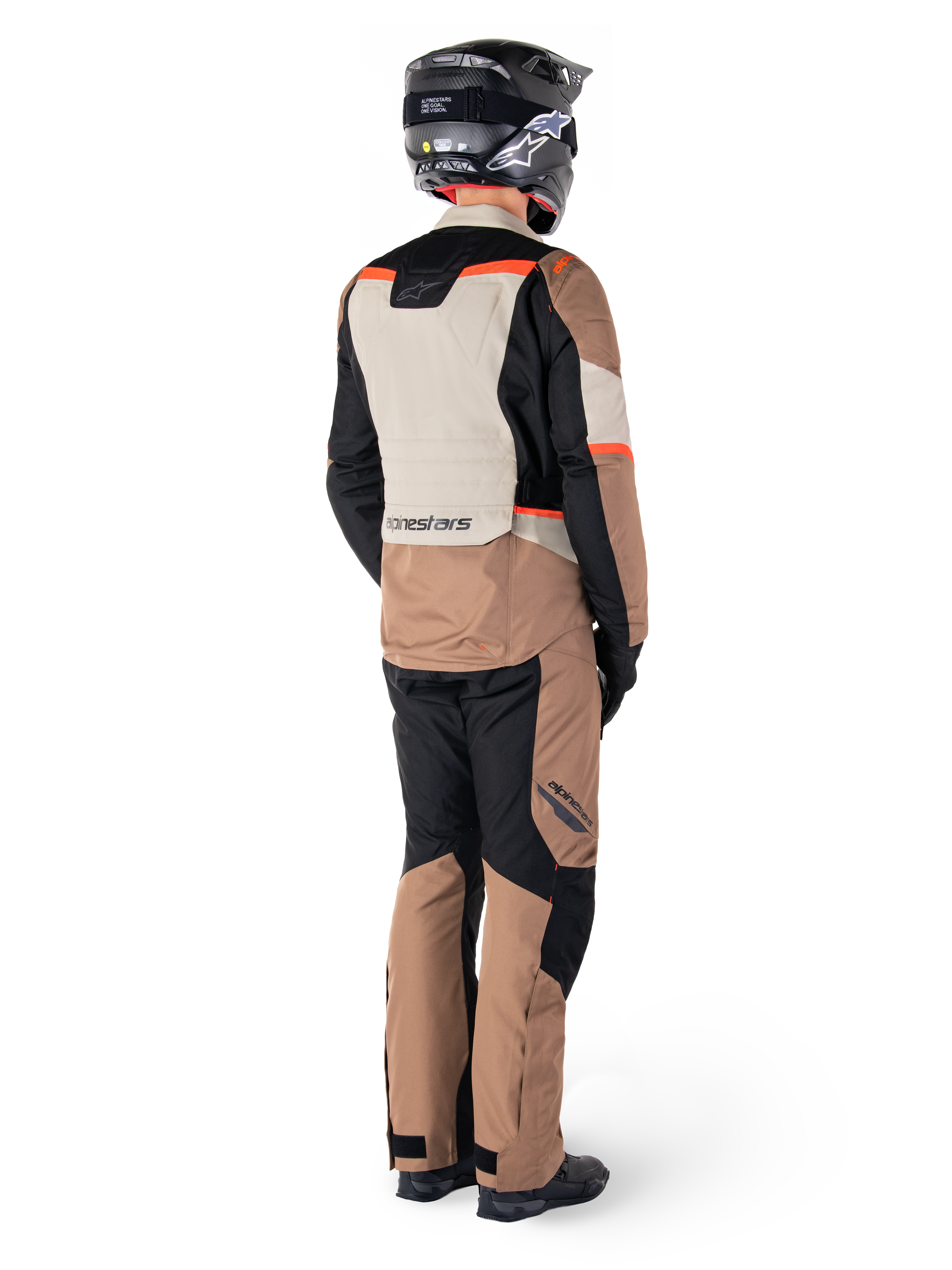 Chaqueta impermeable Alpinestars ST-1, chaqueta de touring de aventura, Dark Khaki Sand Black Red Fluo, vista trasera con pantalones a juego y casco negro, con paneles de bloques de color y detalles en rojo fluorescente.