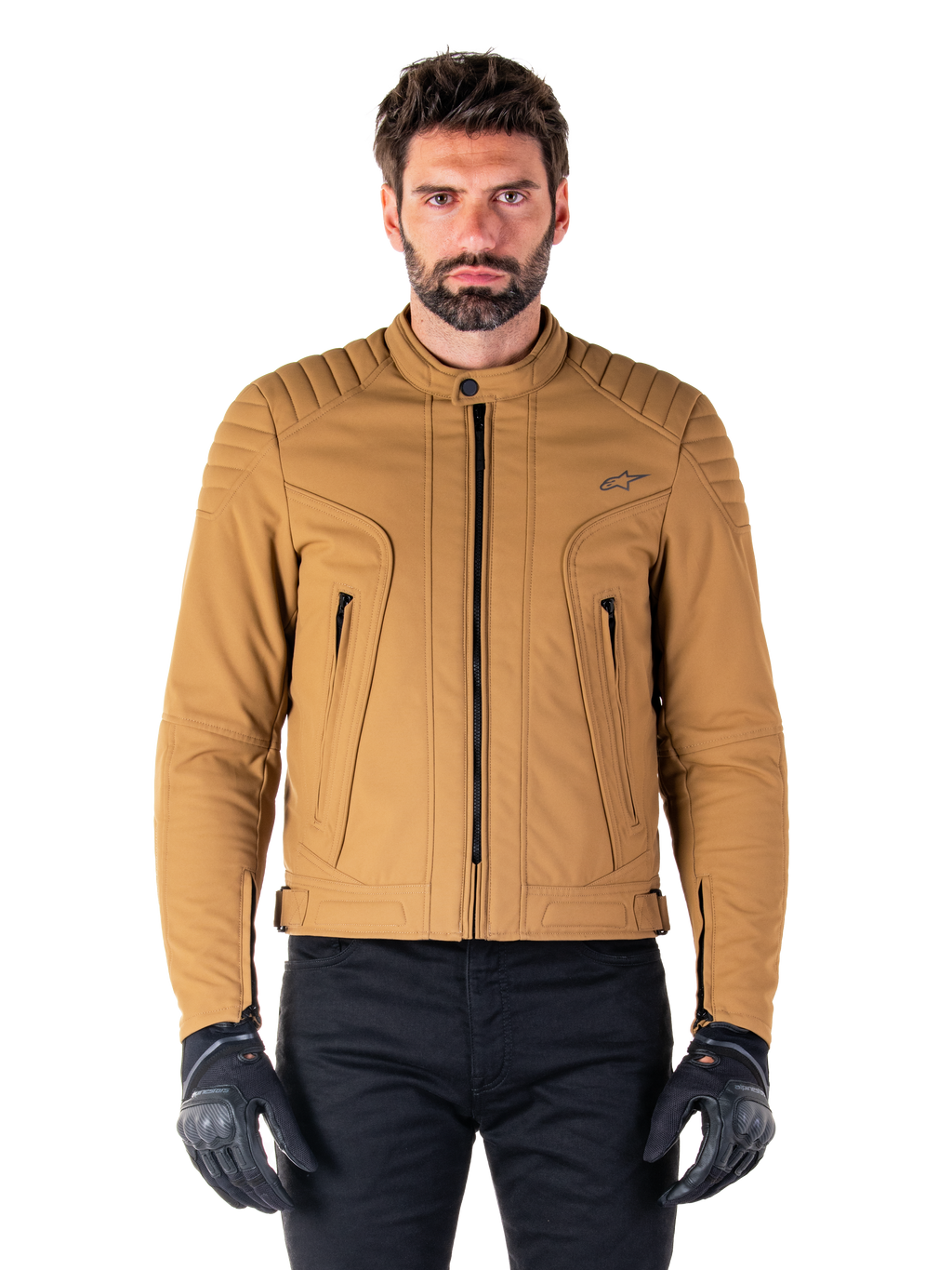 Chaqueta Alpinestars Clayton WR, chaqueta de moto urbana, color Utility Brown Light Gold, textil resistente al agua con hombros acolchados, cuello alto de motorista, detalles de cremalleras negras y logo en el pecho, usada con guantes de protección y pantalones negros