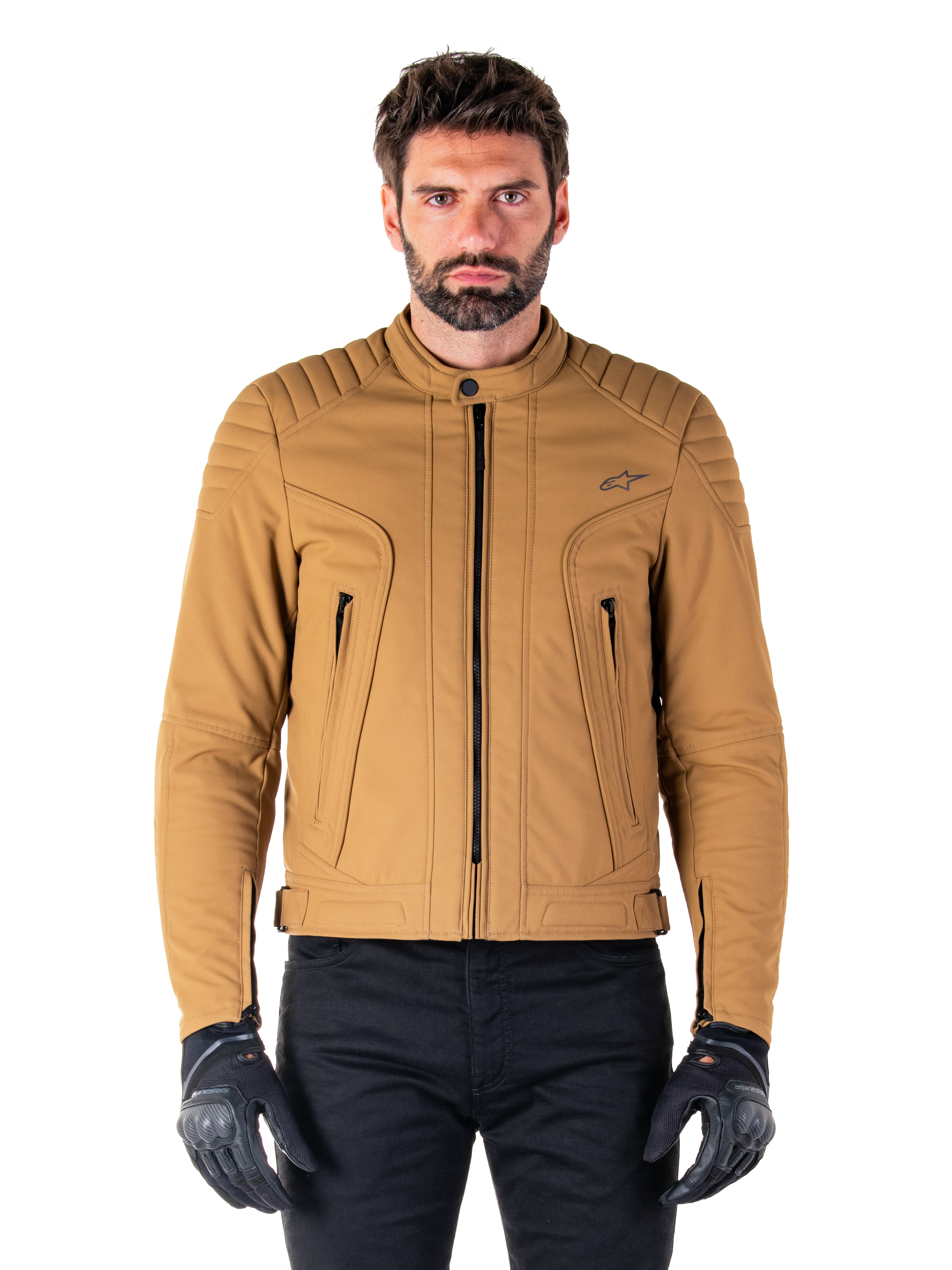 Chaqueta Alpinestars Clayton WR, chaqueta de moto urbana, color Utility Brown Light Gold, textil resistente al agua con hombros acolchados, cuello alto de motorista, detalles de cremalleras negras y logo en el pecho, usada con guantes de protección y pantalones negros
