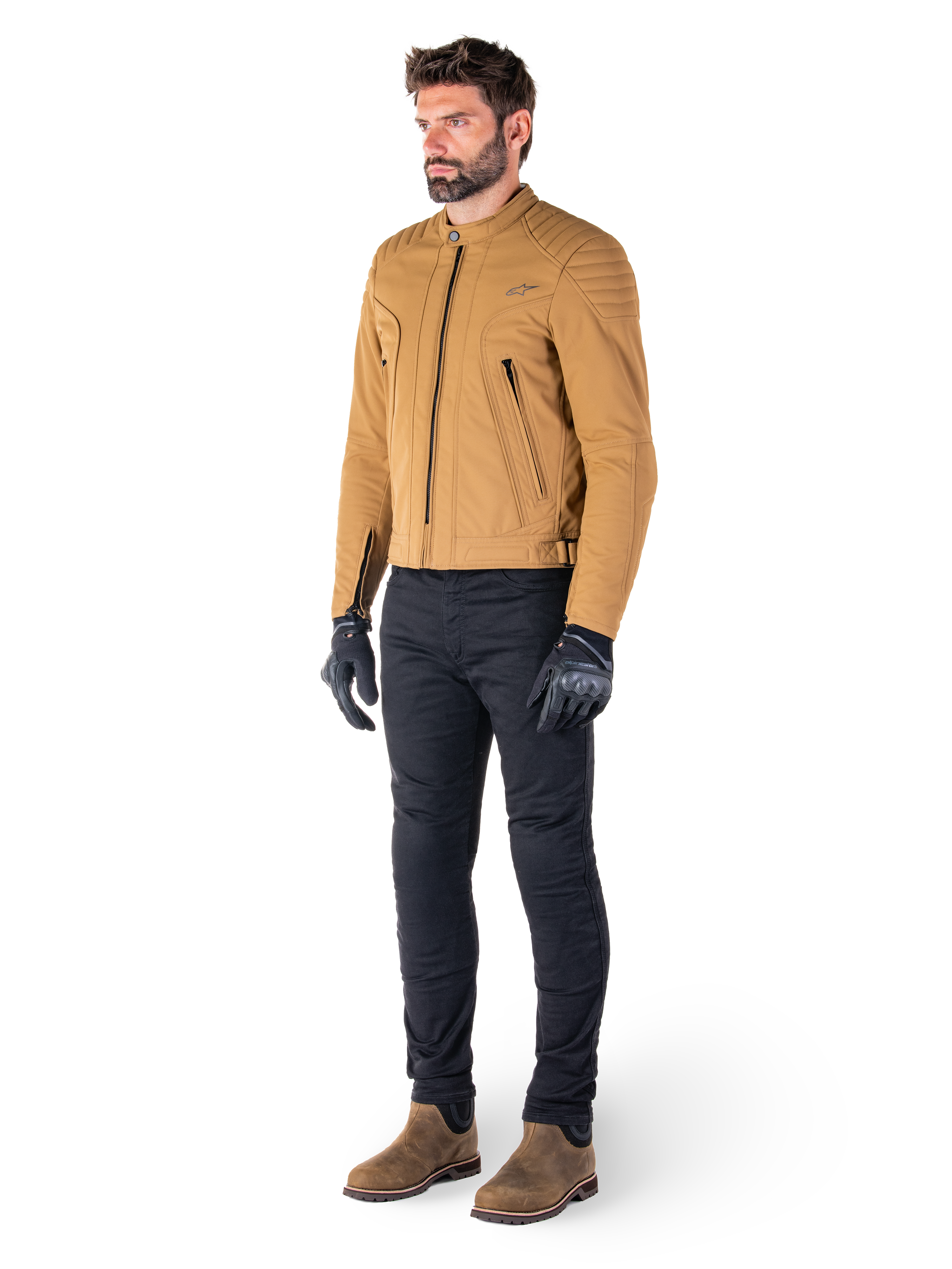 Piloto masculino con la chaqueta Alpinestars Clayton WR en Utility Brown Light Gold, chaqueta de moto urbana contemporánea con detalles acolchados en los hombros, combinada con pantalones negros, guantes negros y botas marrones