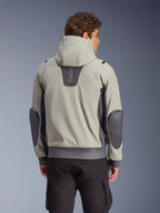 Chaqueta impermeable Alpinestars Moblast en gris hierro y verde salvia oscuro, vista trasera en modelo, chaqueta de moto urbana con capucha con paneles elásticos en gris oscuro y codos reforzados, combinada con pantalones cargo negros
