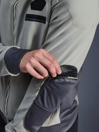 Chaqueta impermeable Alpinestars Moblast, gris hierro y verde salvia oscuro, primer plano que muestra la extracción de la protección Nucleon Flex Plus del bolsillo exterior con cremallera en el codo, equipamiento técnico textil urbano para moto con marca MO.ST.EQ.