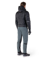 Chaqueta impermeable Alpinestars Mohobbs, negra, vista trasera de chaqueta bomber acolchada con logotipo vertical en relieve en la espalda, combinada con pantalones de conducción grises y guantes negros, equipamiento de motociclismo de estilo urbano