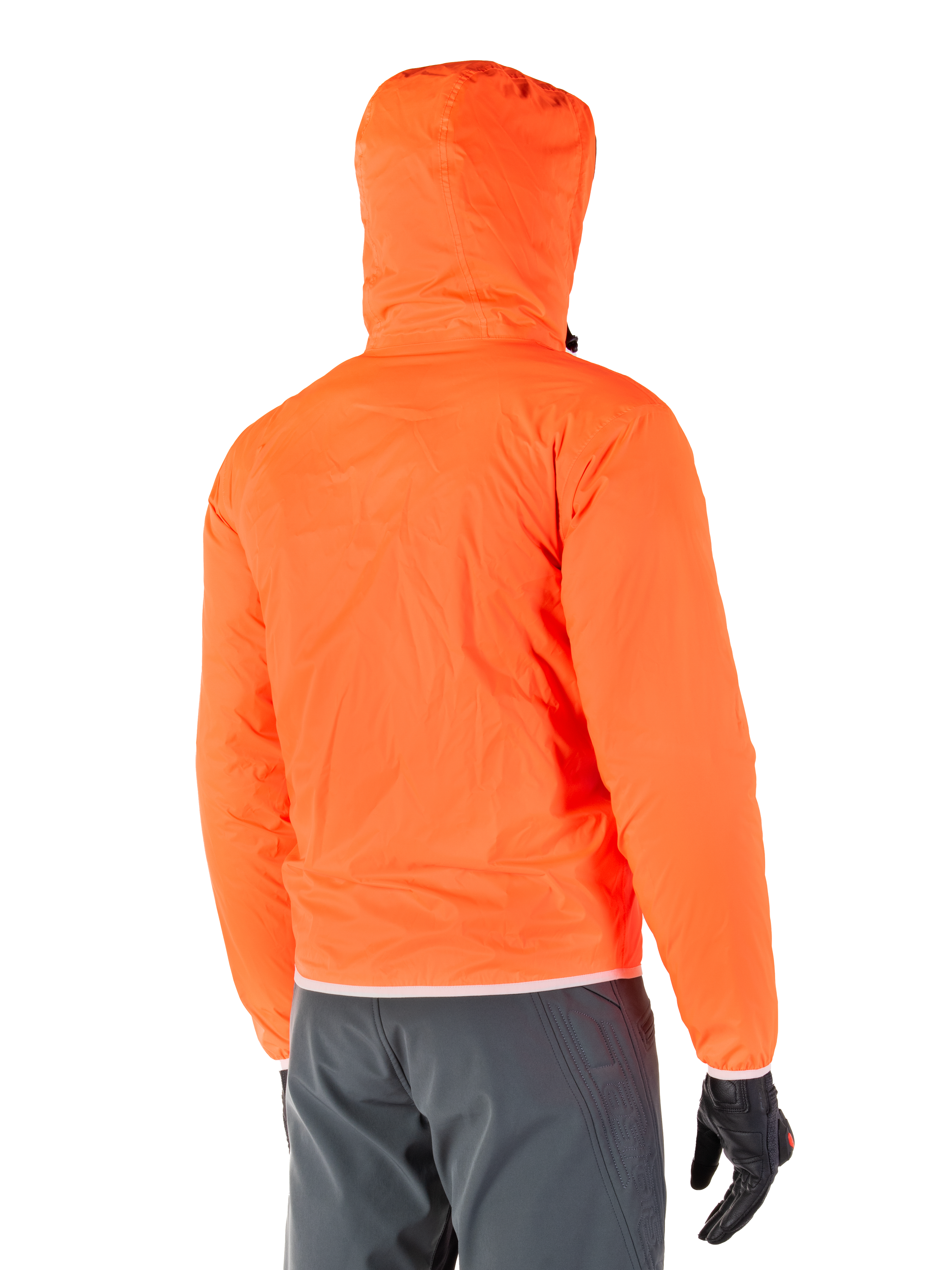 Chaqueta impermeable Alpinestars Mohobbs, forro impermeable de emergencia plegable en naranja flúor brillante, vista trasera que muestra la capucha para tormentas, combinada con pantalones de conducción gris oscuro y guantes negros, equipamiento urbano de motociclismo ligero e impermeable