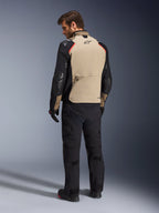 Chaqueta Alpinestars Andes Pro Drystar® XF, chaqueta de motociclismo, color nogal y negro con detalles en rojo, vista trasera en modelo, diseño de turismo de aventura con un gran bolsillo trasero, usada con pantalones de motociclismo y guantes negros.