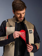 Chaqueta Alpinestars Andes Pro Drystar® XF en Walnut Aluminum, modelo demostrando la inserción del protector de pecho Nucleon rojo en el bolsillo interno, chaqueta de motociclismo de aventura con marca ALL TERRA y logotipos Drystar XF.