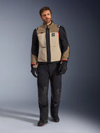 Modelo masculino vistiendo la chaqueta Alpinestars Andes Pro Drystar® XF en Walnut Aluminum, chaqueta de moto adventure touring en color canela y negro con detalles rojos, combinada con pantalones de motociclista, guantes y botas negros, toma de estudio de cuerpo completo de equipamiento de protección.
