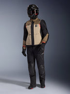 Chaqueta Alpinestars Andes Pro Drystar® XF en Walnut Aluminum, chaqueta de motociclismo de aventura combinada con pantalones negros a juego, casco adventure negro con gafas y botas negras, con paneles en color arena y negro con detalles en rojo.