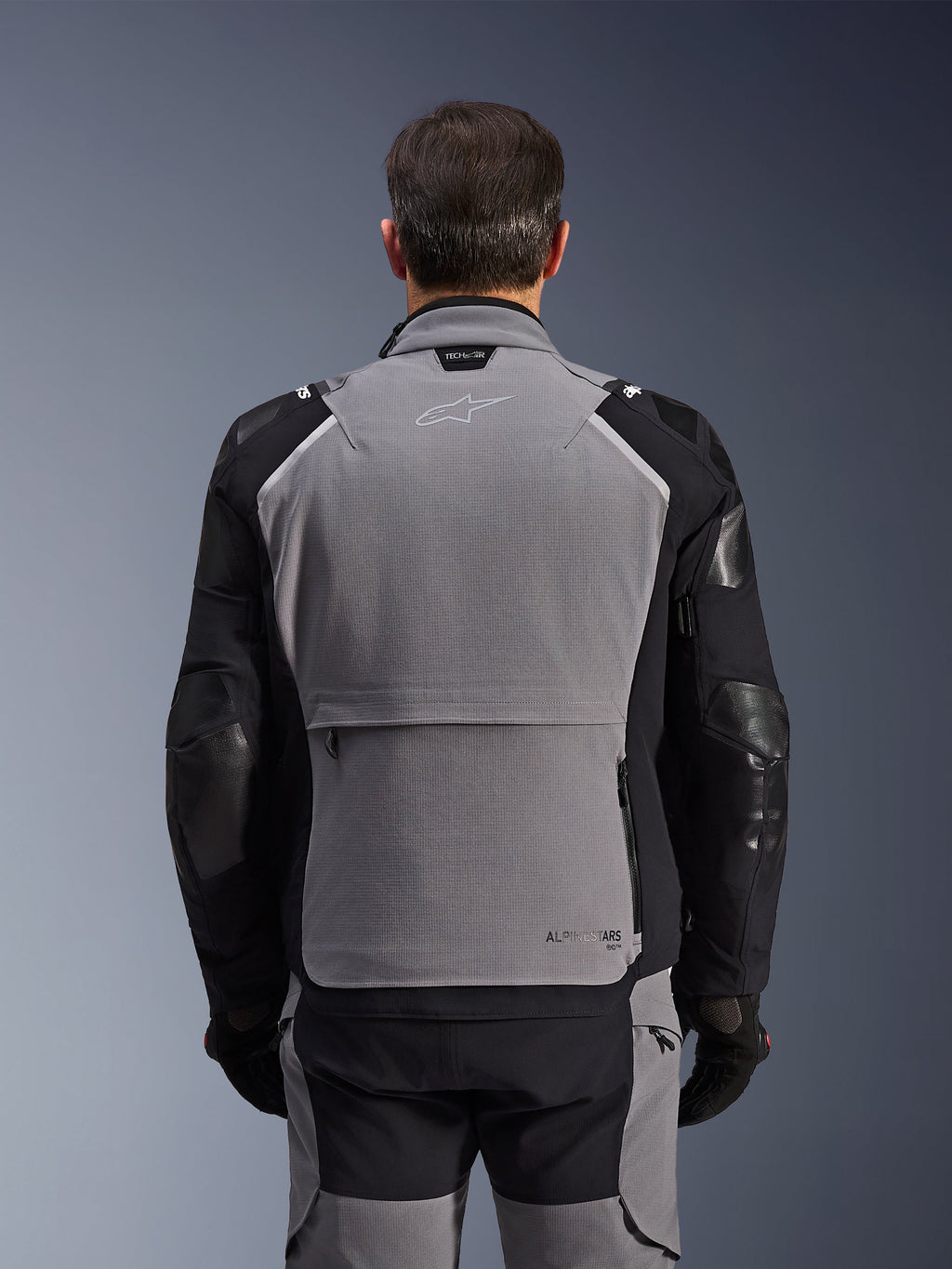 Alpinestars Andes Pro Drystar® XF Jacket, vista trasera, gris oscuro y negro, chaqueta de turismo de aventura con un gran bolsillo de almacenamiento trasero, logotipo Tech-Air® Ready en el cuello y paneles reforzados en los codos.