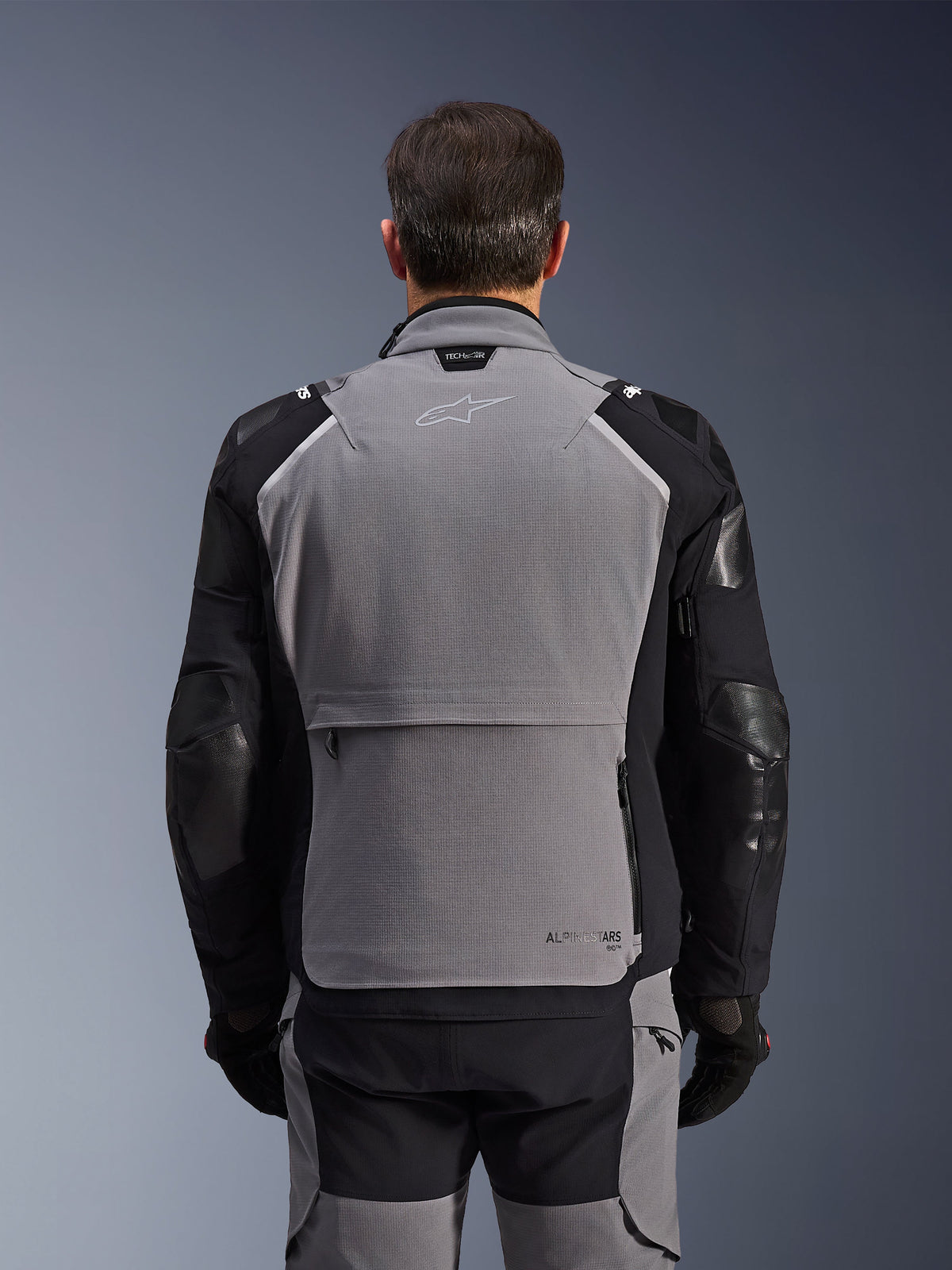 Alpinestars Andes Pro Drystar® XF Jacket, vista trasera, gris oscuro y negro, chaqueta de turismo de aventura con un gran bolsillo de almacenamiento trasero, logotipo Tech-Air® Ready en el cuello y paneles reforzados en los codos.