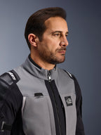 Chaqueta Alpinestars Andes Pro Drystar® XF, chaqueta de aventura para motociclismo, gris oscuro y negro, primer plano del torso frontal y el cuello, con logotipo de Terra y detalle del sistema de hidratación, usada por un hombre en un estudio