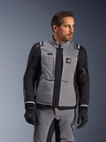 Chaqueta Alpinestars Andes Pro Drystar® XF en gris oscuro y negro, equipamiento de aventura para motociclistas, usada por un hombre con pantalones grises coordinados y guantes negros, con capa laminada de 3 capas, bolsillos utilitarios y logotipo 'Terra' en el pecho