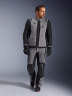 Modelo masculino vistiendo la chaqueta Alpinestars Andes Pro Drystar® XF en gris oscuro y negro, traje de motociclismo de aventura con pantalones y guantes a juego, con una capa de tejido técnico y marca 'All Terra', equipamiento completo para touring de aventura de larga distancia