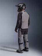 Chaqueta Alpinestars Andes Pro Drystar® XF, chaqueta de aventura para motocicleta, gris oscuro y negro, vista trasera que muestra el panel posterior gris y mangas negras, usada con pantalones a juego y casco negro, equipamiento técnico de conducción para todo clima