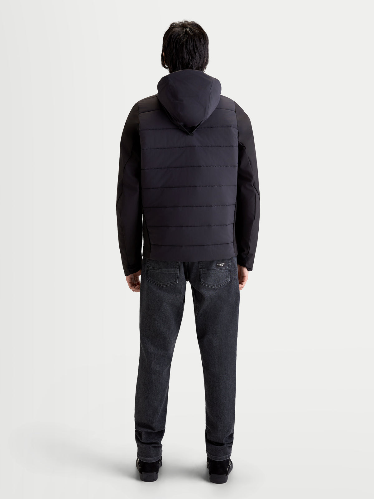 Alpinestars Therma-Tech Waterproof Jacket, men's urban contemporary motorcycle jacket in black, rear profile view on a model wearing the integrated hood system and sonic-welded down construction.