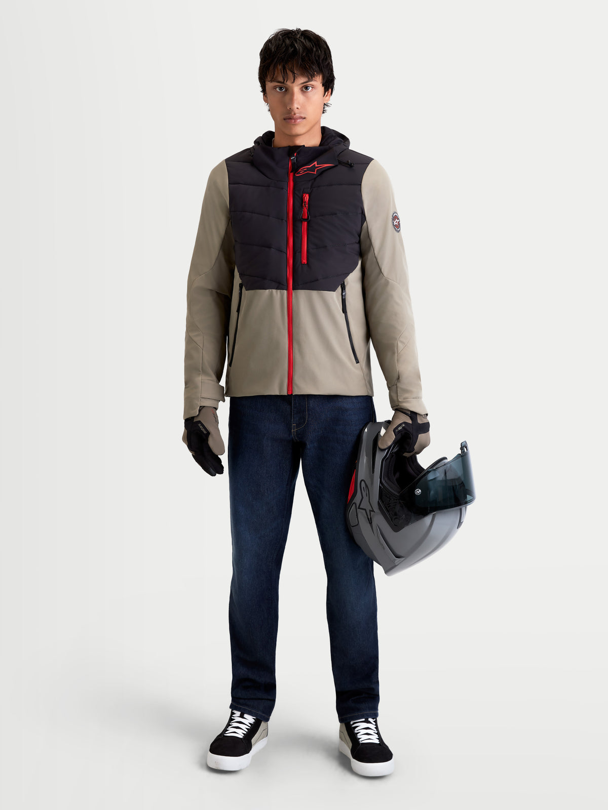Alpinestars Therma-Tech WP Chaqueta, chaqueta de moto urbana y contemporánea de tejido textil para hombre en negro y vetiver, vista frontal completa en un modelo que lleva guantes a juego y sujeta un casco, equipamiento impermeable y térmico para carretera