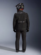 Chaqueta Alpinestars Cusco Drystar, chaqueta de aventura para motociclismo, negra, vista trasera combinada con pantalones a juego y un casco negro y blanco, con logotipos reflectantes de Alpinestars y grandes paneles de ventilación, construcción textil duradera para turismo de aventura por carretera