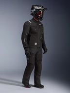 Chaqueta Alpinestars Cusco Drystar®, chaqueta de motociclismo adventure touring negra, usada con pantalones negros a juego y casco integral con gafas, con diseño funcional de múltiples bolsillos, construcción en tejido técnico y marca Drystar en la manga.