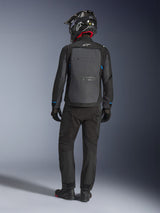 Chaqueta Alpinestars Cusco Drystar®, negro y gris oscuro, vista trasera de un piloto con equipamiento completo de adventure touring, gran panel trasero gris con el logotipo de Alpinestars, detalles azules en las mangas, usada con pantalones negros y casco a juego.