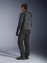 Chaqueta Alpinestars Cusco Drystar®, negro y gris oscuro, vista trasera de tres cuartos que muestra el gran panel de ventilación trasero y detalles azules en las mangas, usada con pantalones y botas de moto negros para un conjunto de touring completo.