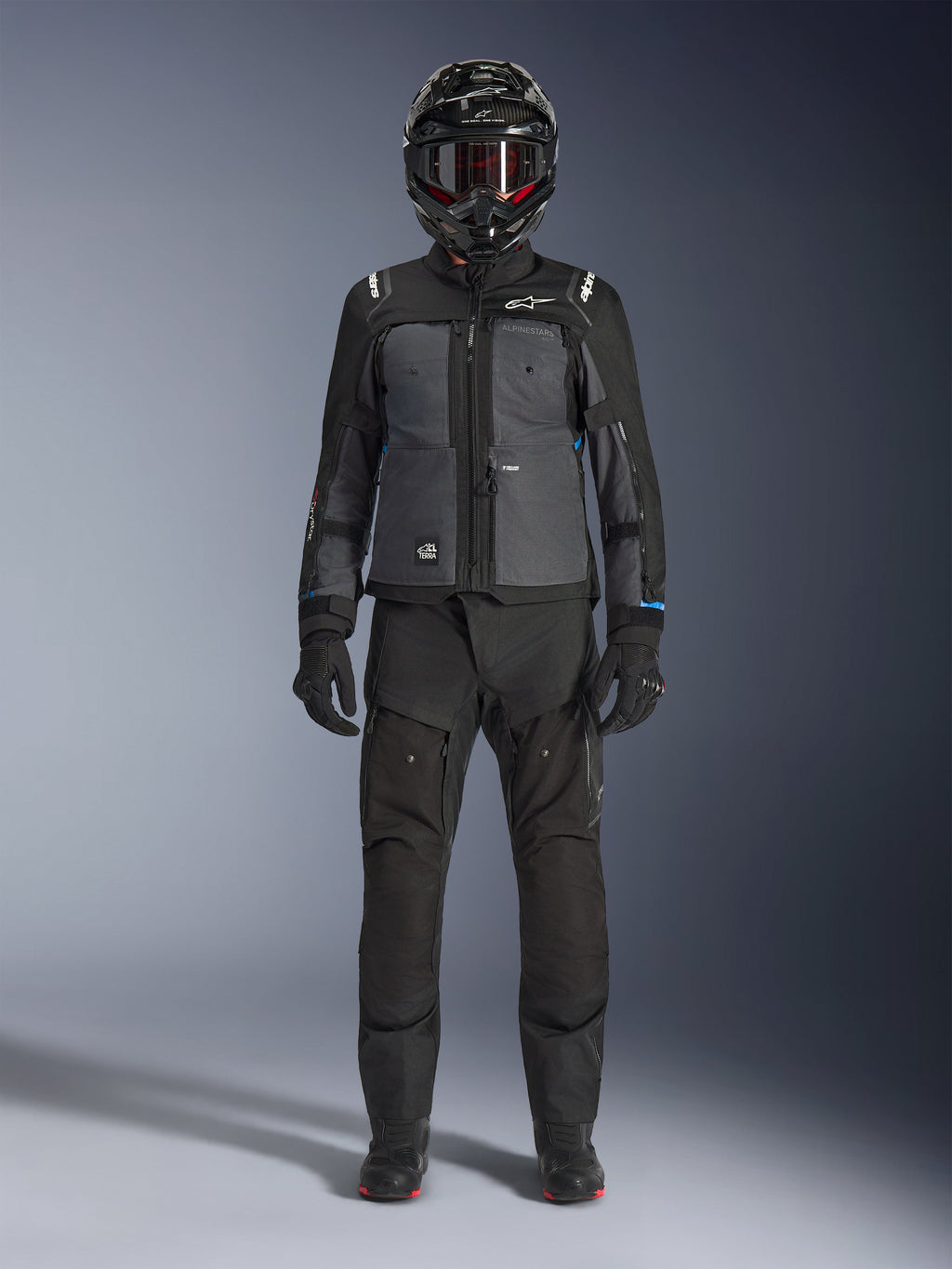 Chaqueta Alpinestars Cusco Drystar®, chaqueta adventure touring en color negro y gris oscuro, combinada con pantalones negros a juego, guantes y casco integral, vista frontal de cuerpo completo, ropa de protección para motociclista