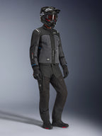 Modelo con la chaqueta Alpinestars Cusco Drystar® en Negro y Gris Profundo, equipamiento completo de motociclismo con casco negro, pantalones técnicos a juego, guantes y botas; construcción en ripstop y softshell para conducción por carretera y adventure touring.