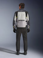 Vista trasera de un motociclista con la chaqueta Alpinestars Cusco Drystar® en color Ice Gray, Mid Gray y Deep Gray, combinada con pantalones y guantes de motociclismo negros, destacando el gran panel de ventilación trasero y el logotipo de Alpinestars.