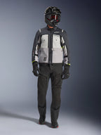 Chaqueta Alpinestars Cusco Drystar®, Ice Gray Mid Gray Deep Gray, chaqueta de motociclismo adventure combinada con pantalones de moto negros, guantes negros y casco negro con gafas, con paneles grises en bloques de color y detalles técnicos para touring y carretera