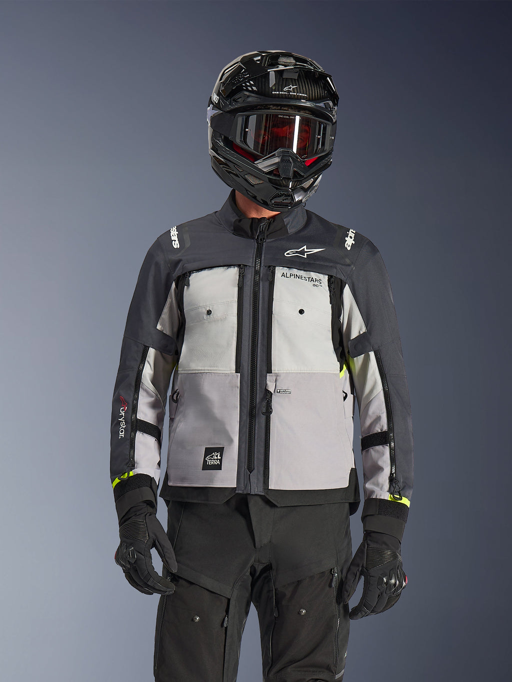 Alpinestars Cusco Drystar® Jacket, chaqueta de adventure touring, en colores Ice Gray, Mid Gray y Deep Gray, con paneles grises de varios tonos, ventilaciones de pecho con cremallera y marca Alpinestars, lucida por un motociclista con casco negro y gafas.