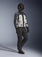 Chaqueta Alpinestars Cusco Drystar® en Ice Gray Mid Gray Deep Gray, toma de cuerpo completo de un motociclista con equipamiento de aventura completo que incluye casco negro con gafas rojas, pantalones negros y guantes a juego, chaqueta textil de moto con paneles de ventilación directa y membrana impermeable.