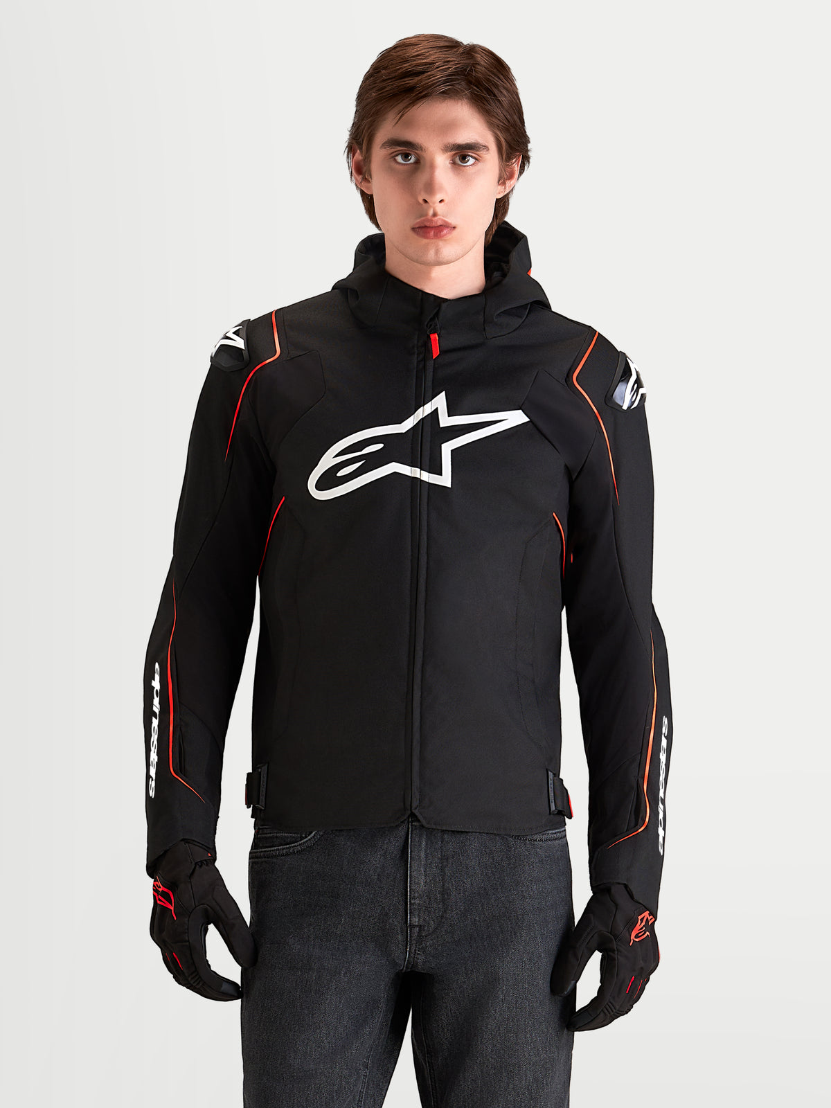 Alpinestars Zaca V2 Waterproof Jacket, chaqueta deportiva de moto para hombre en negro y rojo, con protecciones DFS en los hombros y logo Astar blanco en el pecho, en foto de estudio con modelo