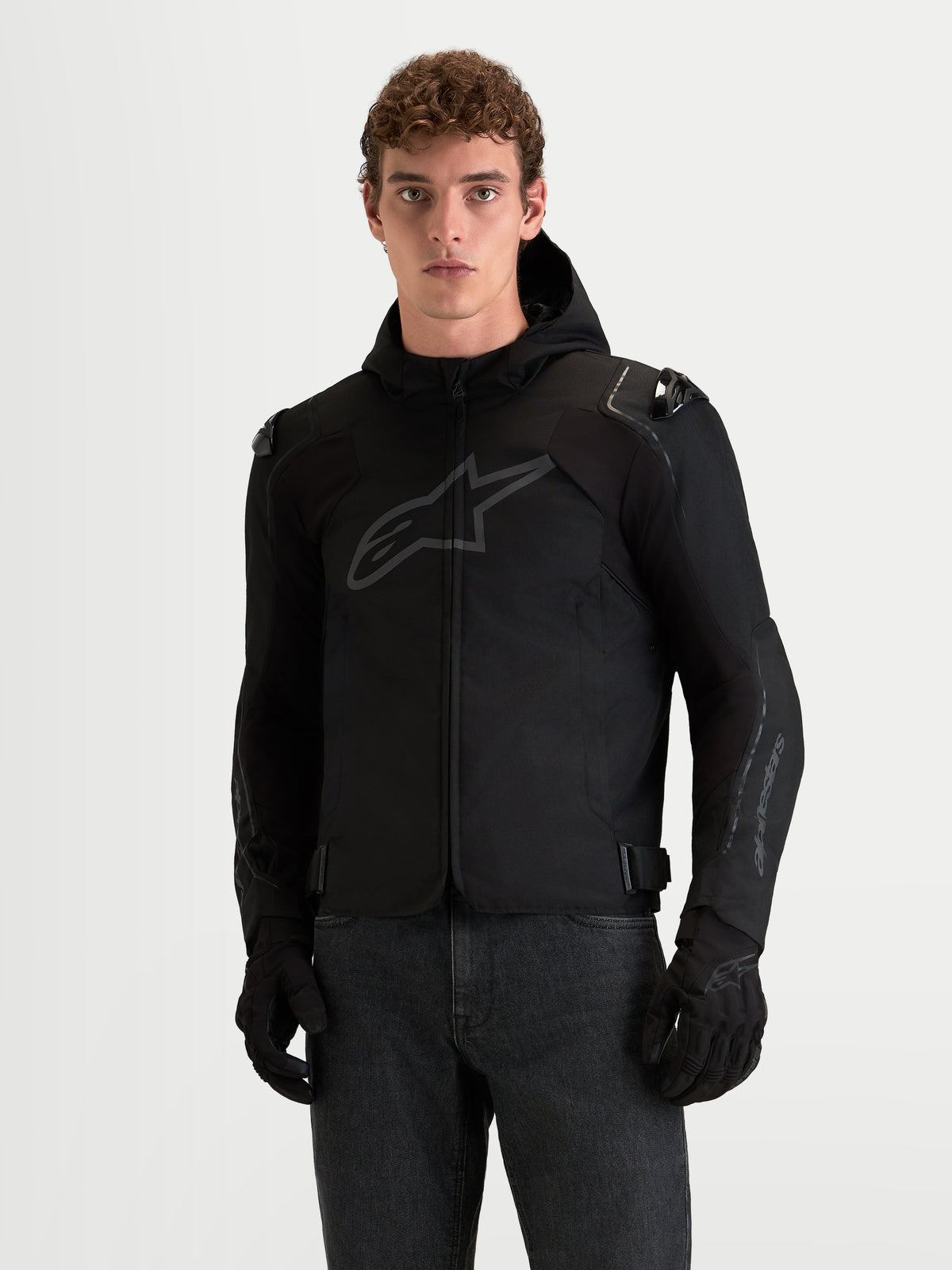 Alpinestars Zaca V2 Waterproof, chaqueta de moto deportiva para hombre, negra, con capucha y protección integrada en los hombros, vista frontal en modelo
