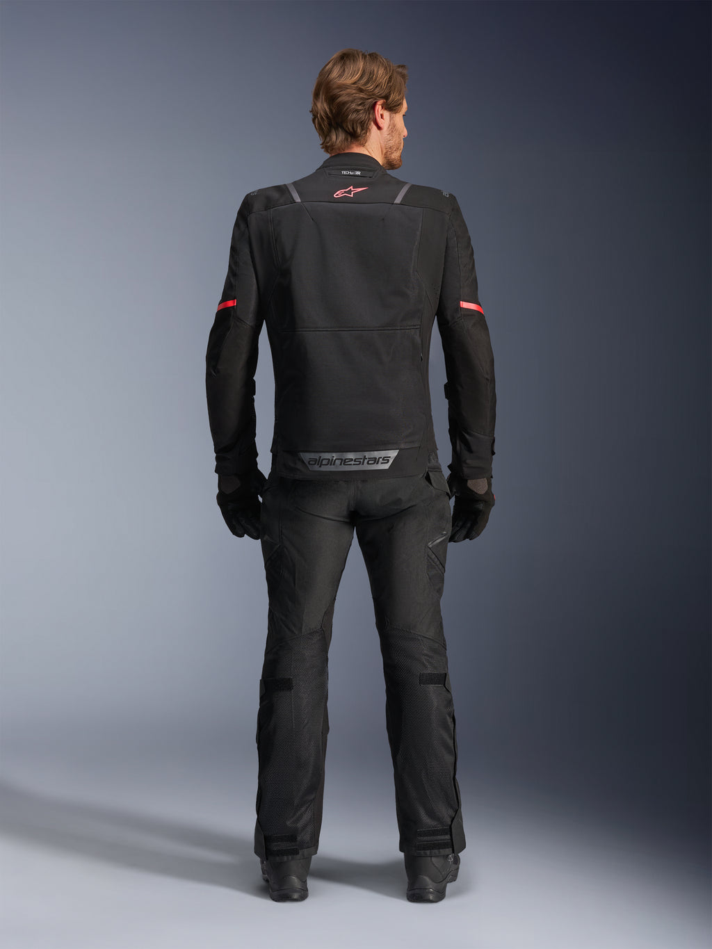 Alpinestars ST-2 Air Jacket, Black, back view of a rider wearing the motorcycle jacket and matching black pants, featuring mesh ventilation panels, red logo on the upper back, and grey Alpinestars branding on the lower back hem