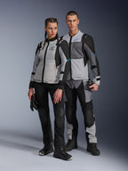 Hombre y mujer con chaquetas Alpinestars Stella ST-2 Air y pantalones técnicos a juego, combinación de colores Ice Gray y Black con detalles en azul, con ventilación de malla y la marca 'ALPINESTARS EXPLORATION EQUIPMENT', toma de pareja en estudio.