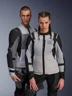 Chaquetas Alpinestars ST-2 Air y Stella ST-2 Air, gris hielo y negro, chaquetas de moto textiles con paneles de malla y perforaciones láser, con la marca 'Alpinestars Exploration Equipment', usadas por modelos masculino y femenino sosteniendo guantes de conducción.