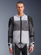 Chaqueta Alpinestars ST-2 Air, chaqueta de moto para hombre, gris hielo y gris oscuro con detalles en negro, amplios paneles de ventilación de malla, frontal perforado con láser, logotipo azul de Alpinestars, cremallera frontal, usada por un modelo con pantalones de moto a juego