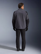 Alpinestars Maxdura Drystar®XF Laminated Armored Shell, chaqueta de motocicleta, gris oscuro y negro, vista trasera de un piloto con equipamiento completo de aventura, capa técnica laminada con paneles reforzados negros en hombros y codos, combinada con pantalones y guantes negros.
