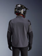 Maxdura Drystar®XF Laminated Armored Shell, chaqueta de moto de aventura, Deep Gray Black, vista posterior que muestra la construcción textil técnica y los paneles reforzados, usada con un casco de fibra de carbono negro, pantalones de montar negros y guantes