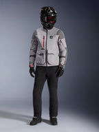 Alpinestars Maxdura Drystar®XF Laminated Armored Shell, chaqueta de aventura en gris medio y gris oscuro con detalles de cremallera en rojo, usada por un piloto con casco negro, gafas rojas y pantalones negros, equipamiento profesional de motociclismo para todo clima