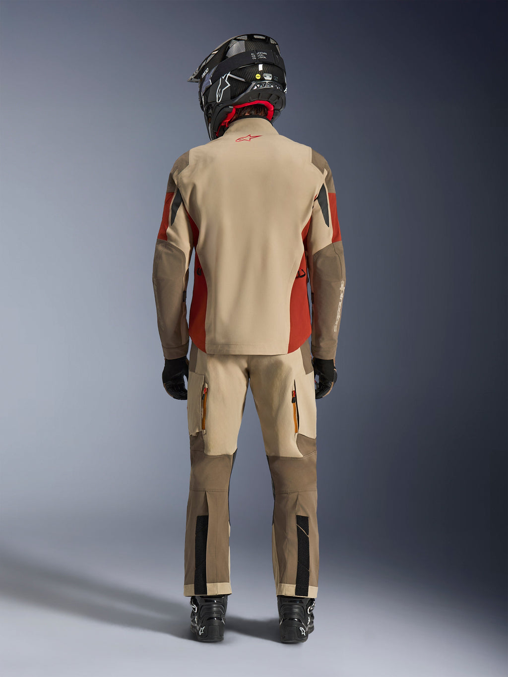 Alpinestars Maxdura Drystar®XF Laminated Armored Shell, chaqueta de moto de aventura y pantalones a juego, combinación de colores Aluminum Walnut y Rust Brown, vista trasera del piloto con casco y botas negras, equipamiento profesional de adventure-touring