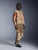 Piloto de aventura vistiendo la chaqueta Maxdura Drystar®XF Laminated Armored Shell en color Aluminum Walnut y Rust Brown con pantalones a juego en nogal y canela, casco negro de fibra de carbono y botas de moto negras, equipamiento técnico de touring para motociclismo de aventura