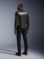Modelo masculino de espaldas vistiendo la chaqueta Alpinestars T-Dyno WR en color negro, gris oscuro y crudo, chaqueta textil de moto con una franja horizontal y el logo de la estrella en la espalda, combinada con pantalones y botas de moto negros, estética de equipamiento urbano para motociclista.