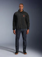 Chaqueta Alpinestars Revved WR en color negro, vestida por un modelo con vaqueros azul oscuro y zapatillas negras, vista frontal, con cierre de botones a presión y logotipo bordado en 3D en el pecho, equipamiento de motociclismo urbano contemporáneo.