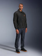 Chaqueta Alpinestars Revved WR en color negro, chaqueta de moto urbana de estilo entrenador usada por un modelo con vaqueros azul oscuro y zapatillas negras, con cierre frontal de botones a presión y logotipo bordado, diseño minimalista y deportivo para la conducción en carretera.