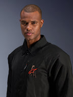 Alpinestars Revved WR Jacket, negra, primer plano de un hombre con la chaqueta de motociclista de satén resistente al agua, con el logotipo 'A' bordado en 3D y la estrella roja de Alpinestars, bolsillo con cremallera en el pecho y diseño con cuello para conducción urbana contemporánea.