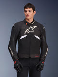 Alpinestars T-GP R V3 Drystar Jacket, chaqueta textil deportiva impermeable, negra y blanca con acentos rojos, con un gran logo de estrella blanca en el pecho y marca blanca en las mangas, usada con guantes de moto negros y rojos