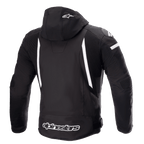 Alpinestars Zaca Waterproof Jacket, chaqueta de moto, negro y blanco, vista trasera que muestra la capucha desmontable con el logo de la estrella blanca, franjas blancas verticales en la espalda, marca Alpinestars en el dobladillo inferior y paneles elásticos acanalados para la movilidad.