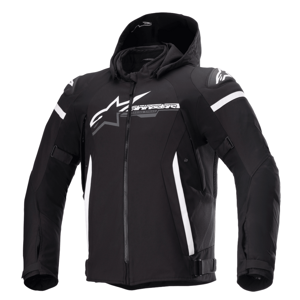 Alpinestars Zaca Waterproof Jacket, chaqueta de moto negra con capucha desmontable, gran logotipo blanco de Alpinestars en el pecho, rayas blancas en la parte superior de los brazos y detalles laterales verticales, cremallera frontal, acolchado reforzado en los hombros, correas ajustables en la cintura y los brazos, construcción en tejido softshell