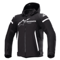 Alpinestars Zaca Waterproof Jacket, chaqueta de moto negra con capucha desmontable, gran logotipo blanco de Alpinestars en el pecho, rayas blancas en la parte superior de los brazos y detalles laterales verticales, cremallera frontal, acolchado reforzado en los hombros, correas ajustables en la cintura y los brazos, construcción en tejido softshell